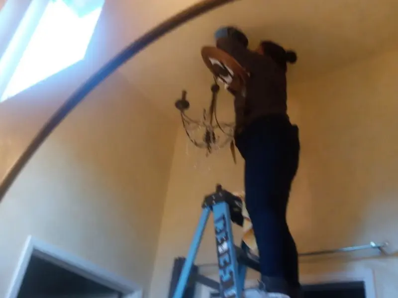 Electrician installing a chandelier in a Yoakum residence